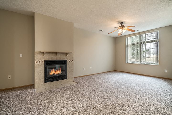 Large living room with lots of natural lighting and a fireplace at Southwind Villas in La Vista NE
